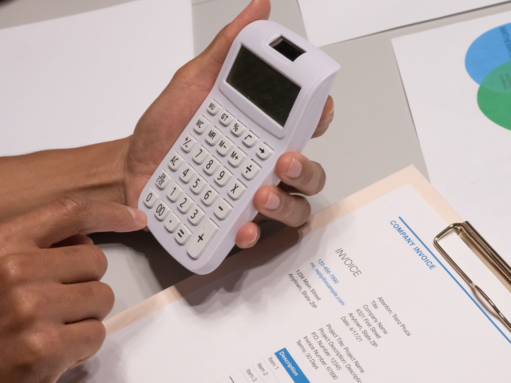 Person manually entering invoice data with paper invoices.